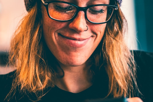 woman wearing black framed eyeglasses and grey knit beanie while using smartphone