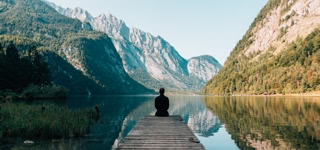 man sitting on gray dock